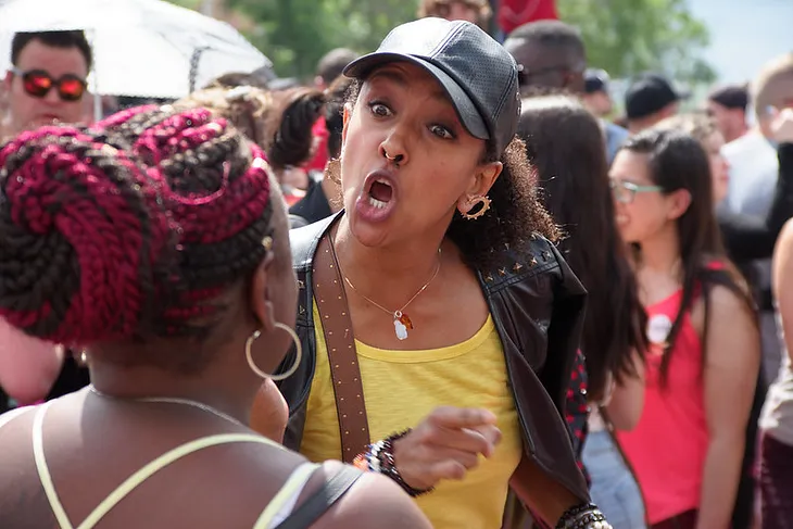 In the middle of a crowd of people, one woman protester berating a bystander who made a comment with which she disagreed