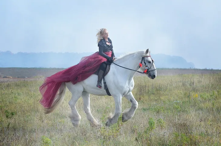 A woman riding a large white horse