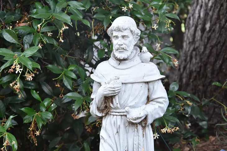 Sculpture of St. Francis in forest setting with birds on his shoulder