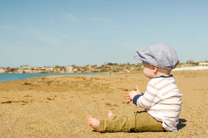 Fully dressed baby on sandy beach