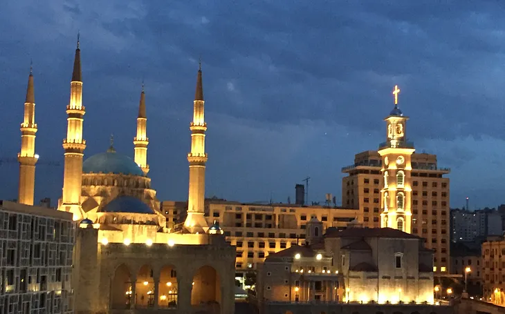 Evening skyline view of Beirut with golden light on the minarets of the mosque and the spire of the Christian church