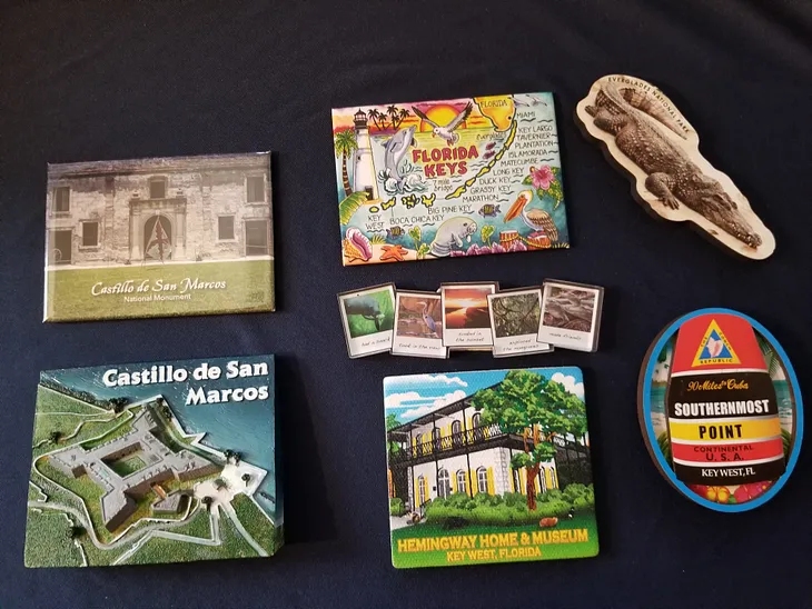 An assortment of magnets collected in Florida: two showing Castillo de San Marcos in St. Augustine, three from the Florida Keys (one shows Hemingway’s home, one a map of the Florida Keys, and one a collection of regional photos), one is an magnet of an Alligator with Florida Everglades written on it, and one is an image of a buoy with this written on it: Emblem with the Conch Republic, 90 miles to Cuba, Southernmost Point Continental U.S.A. Key West, Florida.