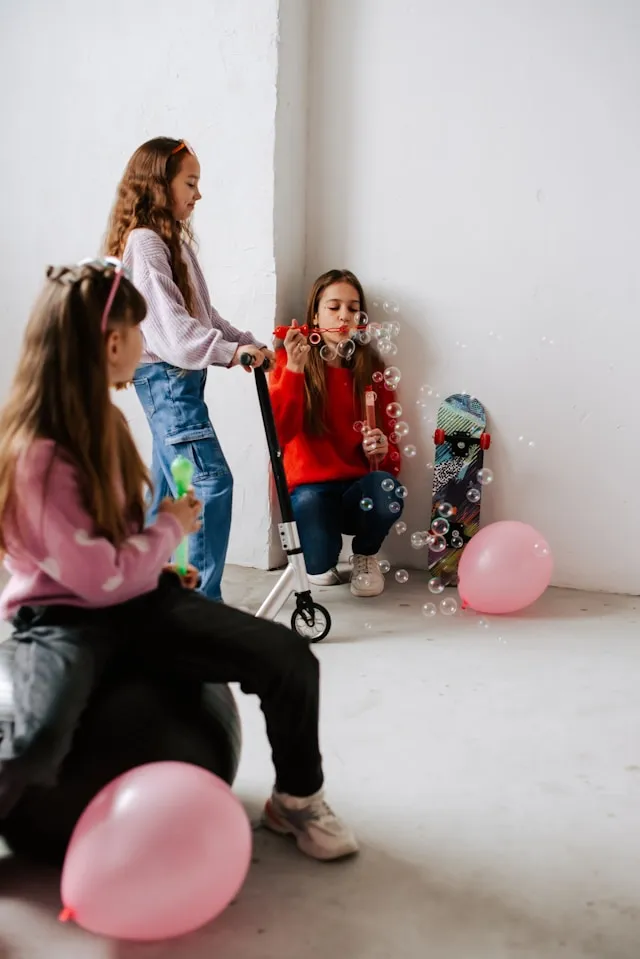 Young girls on a scooter blowing bubbles