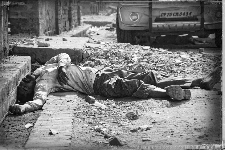 A drunk, possibly spaced out man lying with his head in a gutter