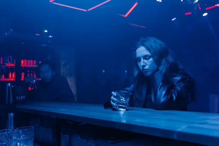 A woman sitting alone in a bar drinking