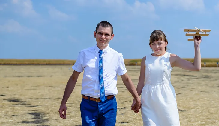 Young couple on honeymoon walking across a beach — Photo