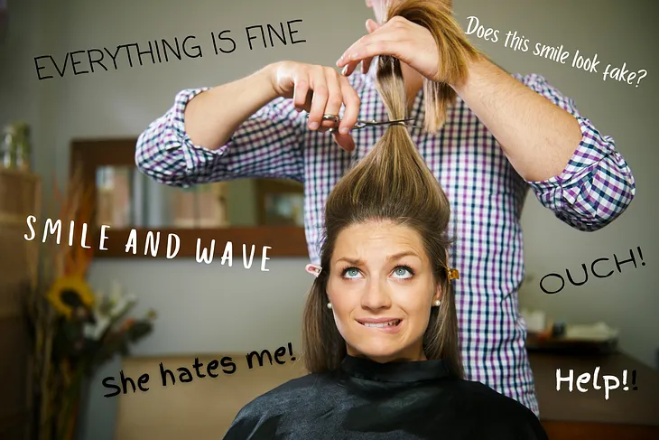 Worried woman biting her lip and looking up, behind her stands a person about to cut off her ponytail. Around them text is floating in the air — “everything is fine,” “does this smile look fake?,” “smile and wave,” “ouch,” “she hates me!” and “help!”. This illustrates what a people pleaser might think when at hairdressers.