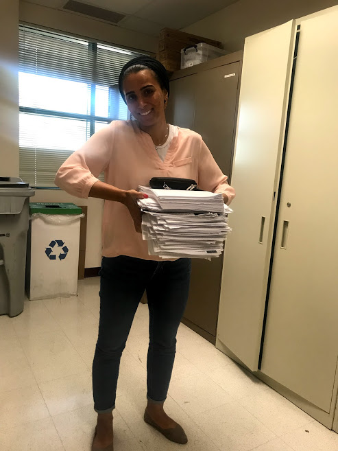 Woman holding a large stack of papers.