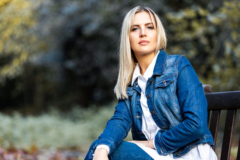 woman in blue denim jacket sitting on park bench