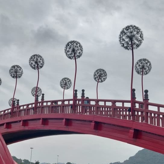 Dandelion shaped light installations on a red wooden footbridge in Sunworld Theme Park, Halong Bay