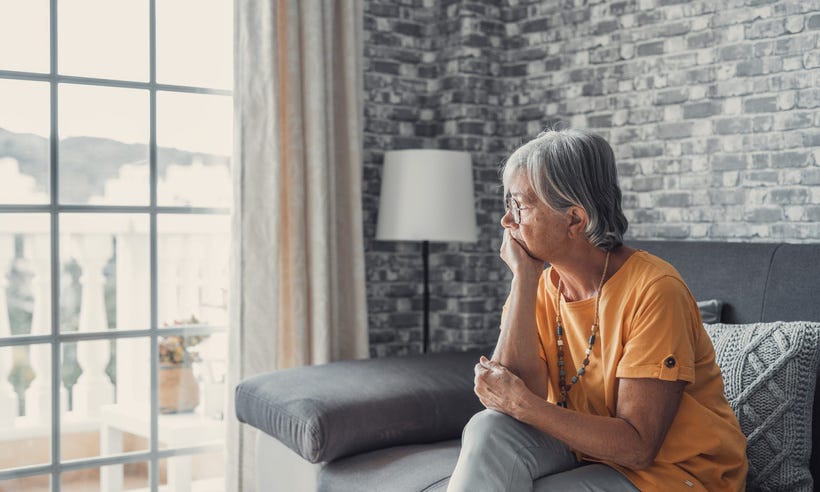 Senior Woman Living Alone Looking Outside The Window Thinking About Her Son