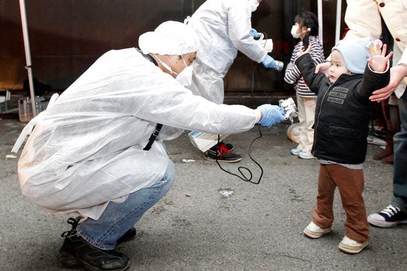 Officials in protective gear check for signs of radiation on children who are from the evacuation area near the Fukushima nuclear plant on March 13, 2011, two days after the accident began. Photo: Kim Kyung-Hoon/Reuters
