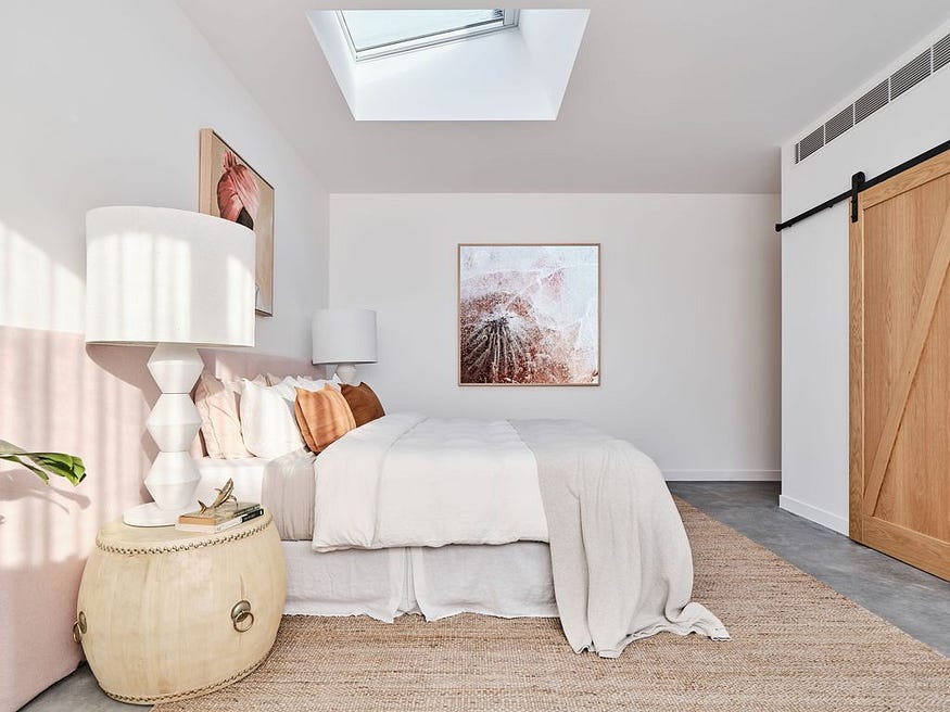 Une chambre principale magnifiquement décorée avec une tête de lit extra longue en lin rose