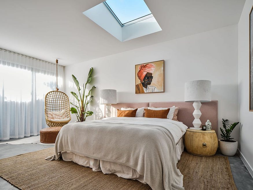 Une chambre principale magnifiquement décorée avec une tête de lit extra longue en lin rose
