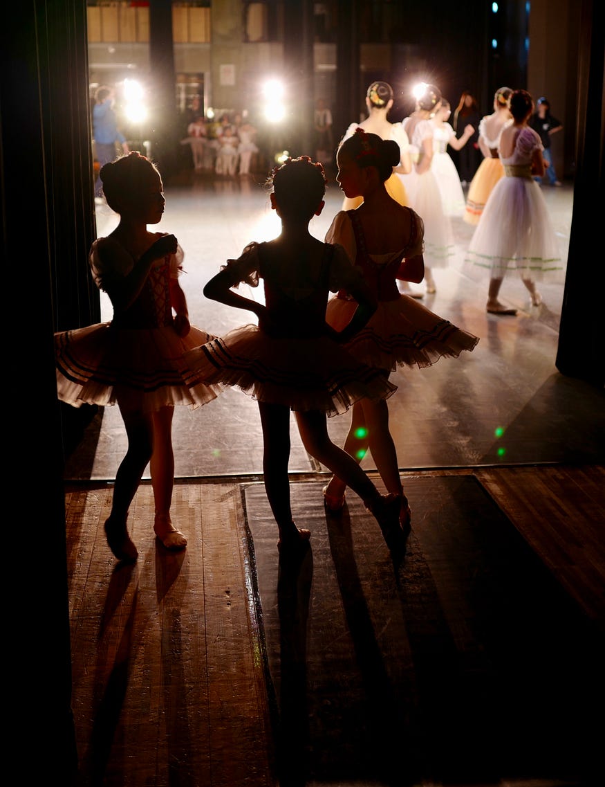 Three young girl ballet dancers waiting in the wings to go on stage