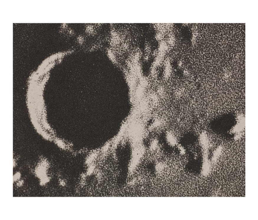 Granulated close-up of a crater, marking a dark hole across the left side and surrounded by rocky landscape.