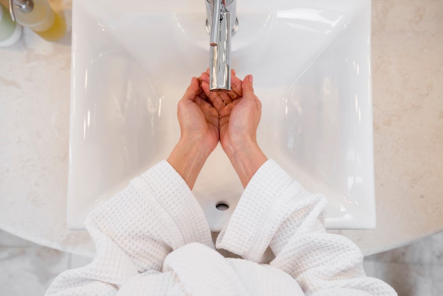 A woman washing hals in a hotel withbathrobe on it.