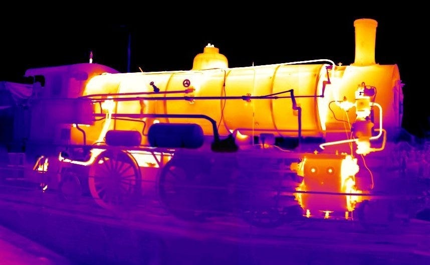 Endless Chaos: The Surprising Rhythms Of Entropy — A steam engine is seen glowing under a thermal camera, showing that it is giving off excess heat to the environment.
