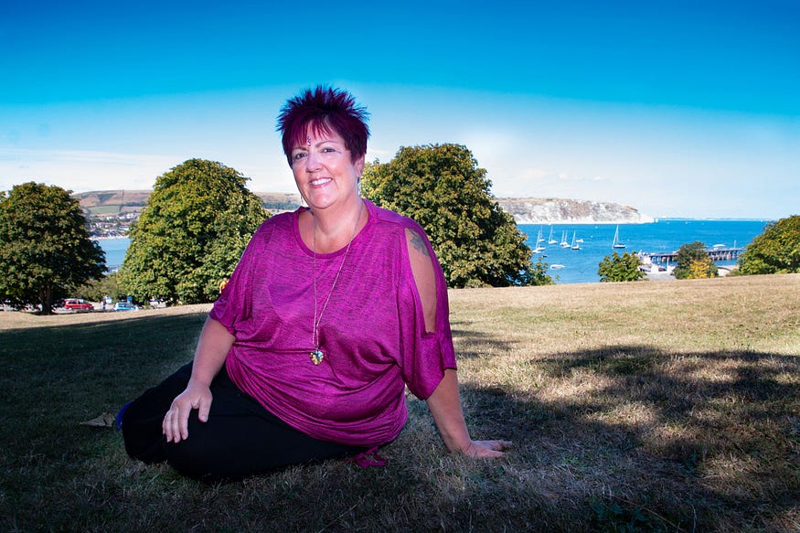 alison smiling in a picturesque field overlooking the sea