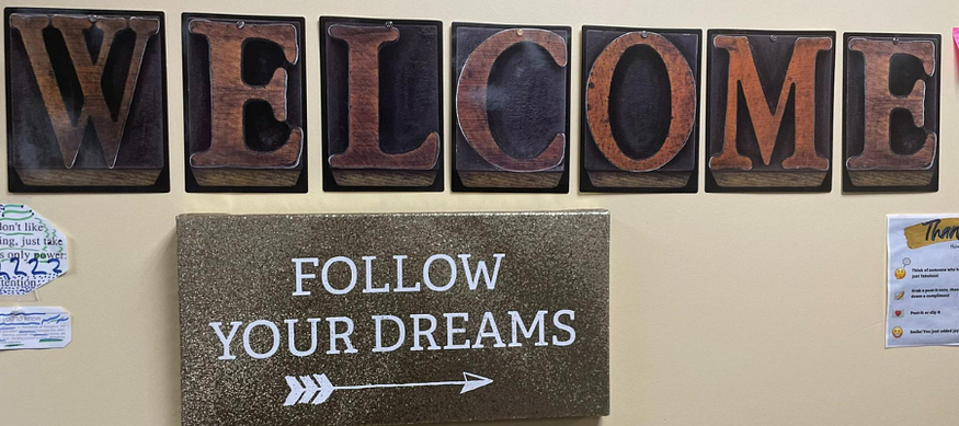 Signs hang on the wall that read “Welcome” and “Follow you Dreams.”