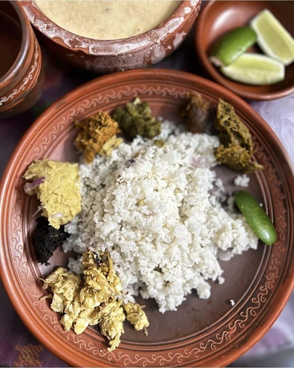A mound of steamed rice enriched with assorted mashed vegetables, mashed fried eggs, nigella seeds, dried fish, lentils, beans, and fresh lime wedges, served on a traditional earthen clay plate. Photo credit: Dr. Tarikul Islam