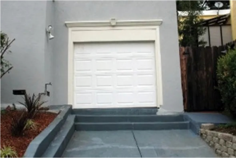 Photo of a house with a garage door that has no driveway access. A set of steps leads directly up to the garage entrance, making it unusable for parking a car.