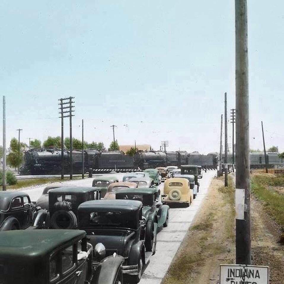 Pennsylvania Railroad stops at Ambridge Station. Traffic waits to pass at 5th & Chase Street, Gary, Indiana.