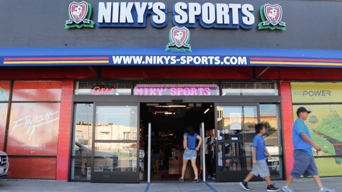 Niky's Sports. Nicolas Orellana stands behind a glass…