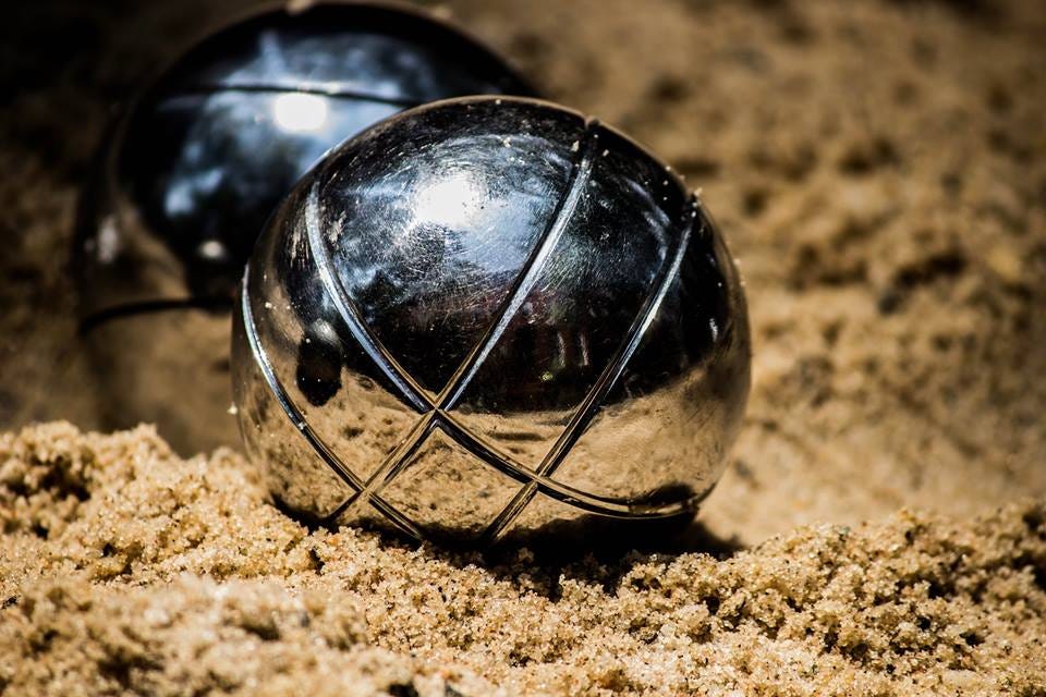 Metal petanque balls and a small wooden jack or cochonnet on sand