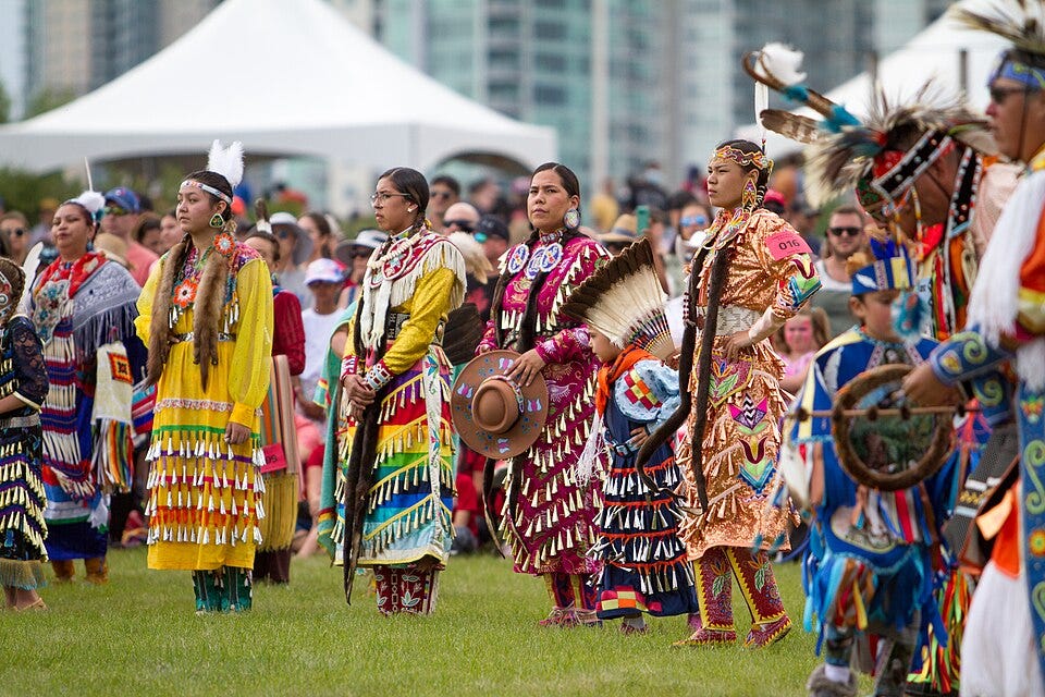 First Nations dancers watch the Canada Day celebrations in Calgary, Alberta, 2022, photograph by Dwayne Reilander, via Wikimedia Commons